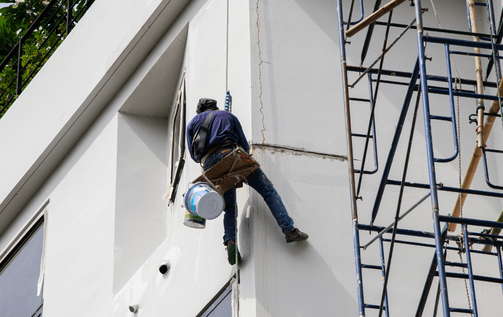Rope access team applying waterproofing system on a multi-storey building